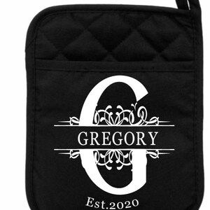 May include: Black quilted oven mitt with a white monogram design. The monogram features the letter G with a decorative flourish and the name "GREGORY" centered below the letter. The year "Est. 2020" is printed below the name.