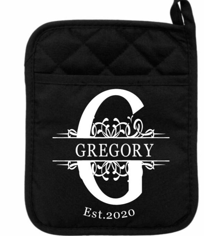 May include: Black quilted oven mitt with a white monogram design. The monogram features the letter G with a decorative flourish and the name "GREGORY" centered below the letter. The year "Est. 2020" is printed below the name.