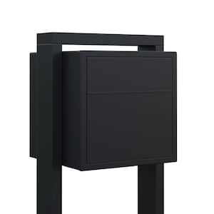 May include: A black metal mailbox with a rectangular opening and a horizontal bar across the top. The mailbox is mounted on two vertical posts.