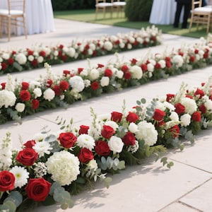 Puede incluir: Filas de arreglos florales con rosas rojas, hortensias blancas y vegetación. Las flores están dispuestas de forma lineal, creando un camino. El escenario parece ser un evento al aire libre, posiblemente una boda o ceremonia.