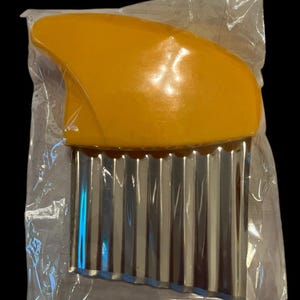 May include: A yellow plastic handled kitchen tool with a stainless steel wavy blade for making decorative potato chips.