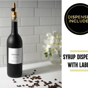 K&ouml;nnte beinhalten: Eine schwarze Glasflasche mit einem goldenen Dosierer und einem wei&szlig;en Etikett mit der Aufschrift "Vanille-Geschmackss сироп". Die Flasche steht auf einer wei&szlig;en Oberfl&auml;che mit Kaffeek&ouml;rnern, die um sie herum verstreut sind. Das Bild zeigt auch einen goldenen Kreis mit dem Text "Sirupspender mit Etiketten" und einen schwarzen Kreis mit dem Text "Spender inklusive".