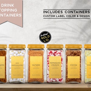 May include: Six glass jars with gold lids and labels. The labels have the names of different drink toppings: Cinnamon, Mini Marshmallows, Nutmeg, Peppermint Crunch, Cocoa, and White Chocolate. The jars are arranged in a row on a wooden surface. The text "new gold lid" is in a circle above the jars.