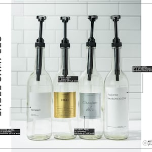 May include: Four clear glass bottles with black pump dispensers, labeled with the flavors "caramel", "Chai", "Cinnamon Dolce", and "Toasted Marshmallow". The labels are white, gold, and silver, with the text "LABEL SAMPLES" on the left.
