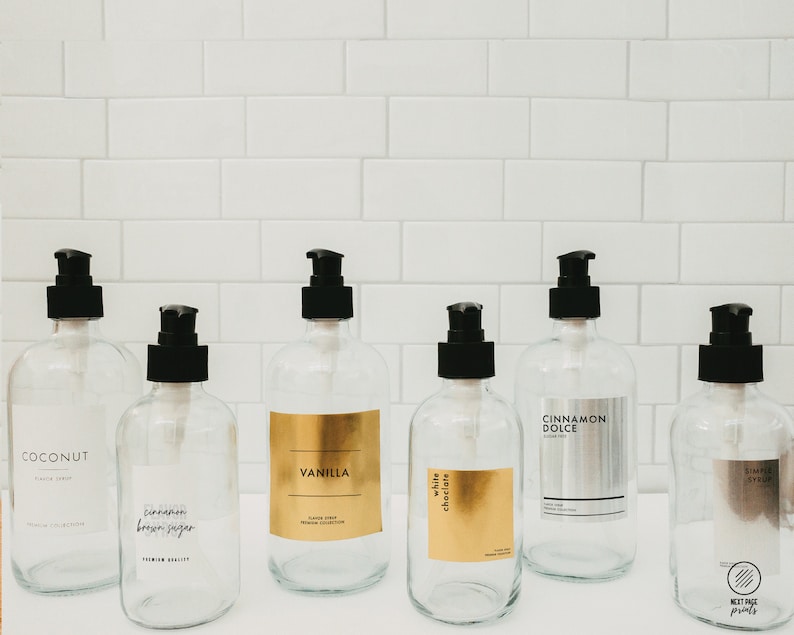 Puede incluir: Seis botellas de vidrio transparente con tapas de bomba negras y etiquetas. Las etiquetas tienen letras doradas y enumeran diferentes aromas: Coco, Canela Az&uacute;car Moreno, Vainilla, Chocolate Blanco, Canela Dolce y Jarabe Simple.