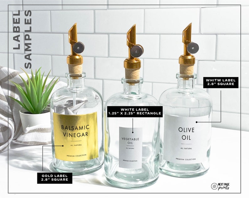May include: Three glass bottles with gold, white, and gold labels. The bottles are filled with liquids and have gold and black pump tops. The labels have text that reads "Balsamic Vinegar", "Vegetable Oil", and "Olive Oil". The labels also include the size and shape of the label.