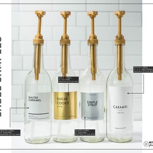 May include: Four clear glass bottles with gold-colored pumps and labels. The labels read "Salted Caramel", "Sugar Cookie", "Simple Syrup", and "Caramel". The text "Label Samples" is on the left side of the image.