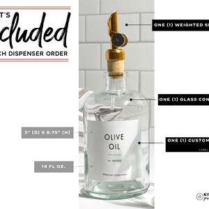 May include: A clear glass bottle with a gold weighted spout and a white label that says "Olive Oil" in black text. The bottle is 3 inches in diameter and 8.75 inches tall and holds 14 fluid ounces. The bottle is part of a set that includes a custom label and a glass container.