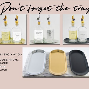 May include: Three sets of glass bottles with labels and gold spouts, each set displayed on a matching gold, silver, or black tray. The bottles are labeled with various flavors, including cinnamon, pumpkin spice, red wine vinegar, vegetable oil, vanilla, and hazelnut. The trays are 3.75 inches wide by 9 inches long.