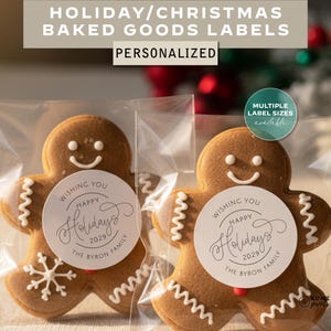 May include: Two gingerbread man biscuits in clear packaging, each with a white circular label that reads "Wishing You Happy Holidays 2029 The Byron Family." The image also includes text that says "Holiday/Christmas Baked Goods Labels Personalized."