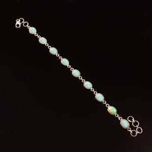 May include: A silver bracelet with oval-shaped turquoise gemstones. The bracelet has a lobster clasp closure and is made of sterling silver.