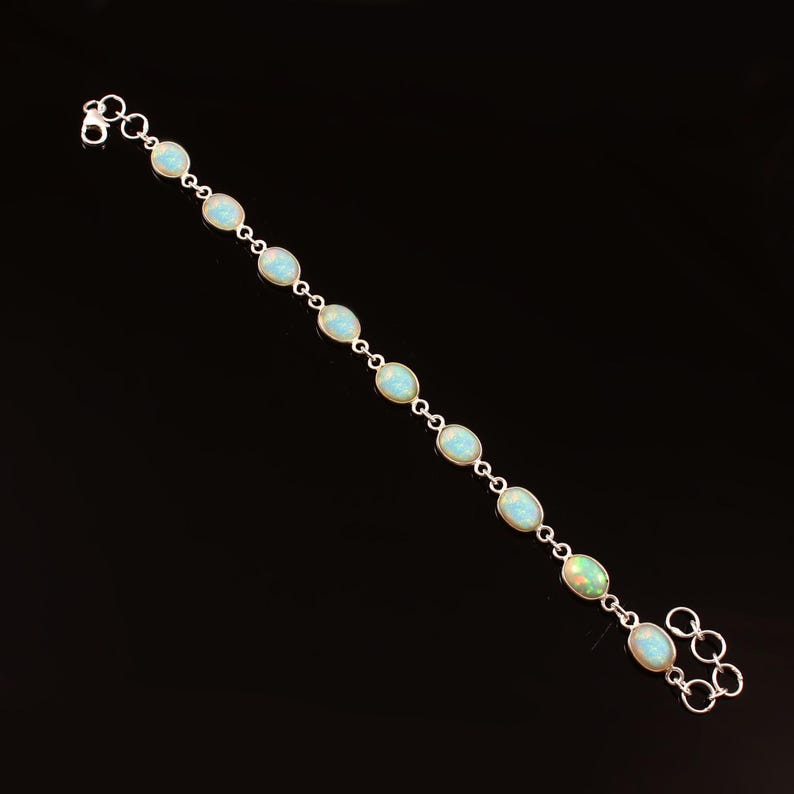 May include: A silver bracelet with oval-shaped turquoise gemstones. The bracelet has a lobster clasp closure and is made of sterling silver.