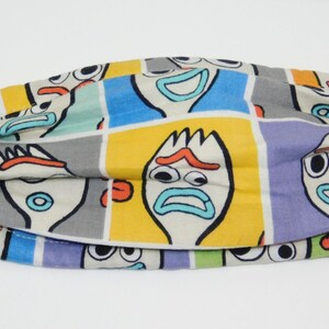 May include: A reusable face mask with a colorful pattern featuring multiple images of the character Forky from the Toy Story movie franchise. The mask has adjustable ear loops and is made of a soft, breathable fabric.