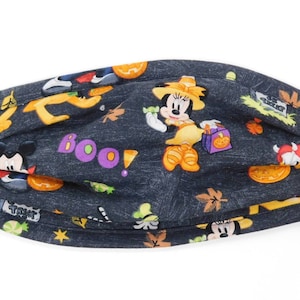 Op de afbeelding: Een zwart stoffen mondkapje met een Halloween-thema. Het masker heeft Mickey Mouse, Minnie Mouse en pompoenen. De tekst "Boo!" staat op het masker gedrukt.