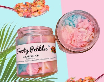 May include: A glass jar of pink and blue sugar scrub with the label "Frooty Pebbles Sugar Scrub" and a list of ingredients. The scrub is topped with colorful cereal pieces.