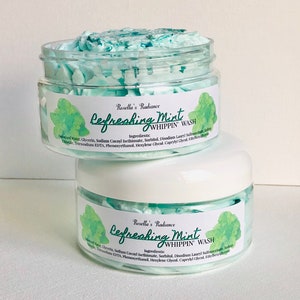 May include: Two clear jars of Refreshing Mint Whippin' Wash, one stacked on top of the other. The top jar contains light blue, whipped soap. Each jar has a label with the text "Refreshing Mint Whippin' Wash" and "Rosella's Radiance".