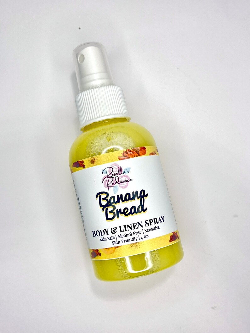 May include: A yellow bottle with a white spray nozzle and a white label that says "Borella's Radiance Banana Bread BODY & LINEN SPRAY Skin Safe | Alcohol Free | Sensitive Skin Friendly | 4 oz."