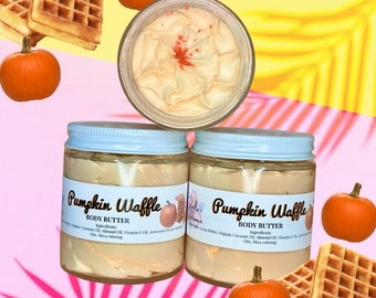 May include: Three glass jars of pumpkin spice body butter with white lids. The jars are stacked on top of each other. The body butter is a light orange colour and has a whipped texture. The jars are surrounded by images of pumpkins and waffles.