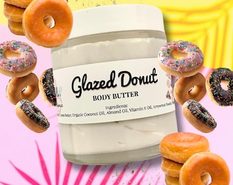 Może przedstawiać: Szklany słoik z białym masłem do ciała z etykietą, na której widnieje napis "Glazed Donut Body Butter" i lista składników: "Masło shea, organiczny olej kokosowy, olej migdałowy, olej witaminy E, proszek z korzenia strzałkowego". Słoik jest otoczony kolorowymi pączkami z posypką.