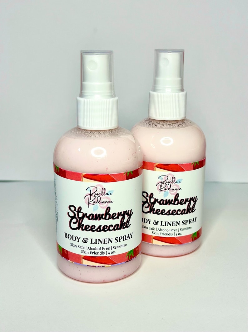 Puede incluir: Dos botellas rosas de spray para el cuerpo y la ropa de fresa y cheesecake. Las botellas est&aacute;n etiquetadas "Borella's Radiance Strawberry Cheesecake Body & Linen Spray" y presentan un dise&ntilde;o de fresa y cheesecake. Cada botella contiene 118 ml.