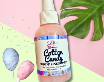May include: A clear bottle with a pink liquid and a white spray top. The bottle has a pink and white label with the text "Rovell Radiance Cotton Candy BODY & LINENSPRAY Skin Safe | Alcohol Free | Sensitive Skin Friendly | 4 oz."