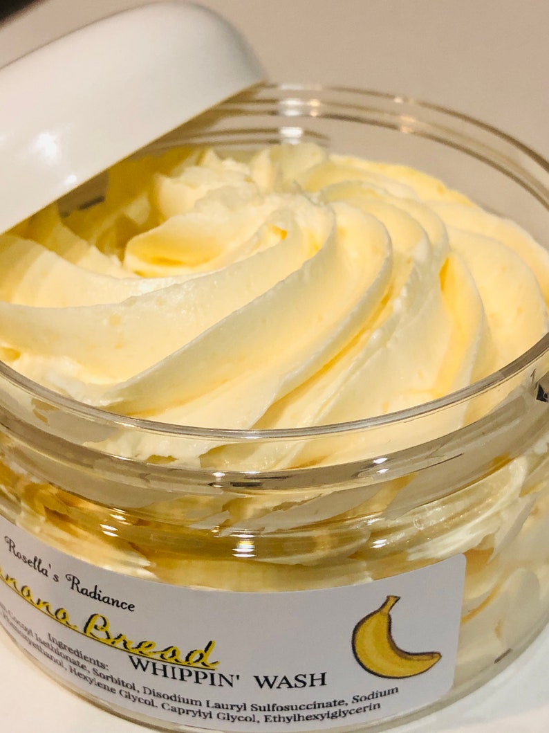 May include: A jar of Rosella's Radiance Banana Bread Whippin' Wash. The product has a whipped, creamy texture and a light yellow colour. The jar is clear with a white lid. A label with a banana illustration is visible.