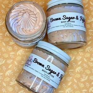 Puede incluir: Dos tarros de vidrio de manteca corporal con tapas blancas. Los tarros est&aacute;n llenos de un remolino de manteca corporal marr&oacute;n claro y morado. Las etiquetas en los tarros dicen "Brown Sugar & Fig" y enumeran los ingredientes: manteca de cacao, aceite de coco org&aacute;nico, aceite de almendras, aceite de vitamina E y colorante mica.