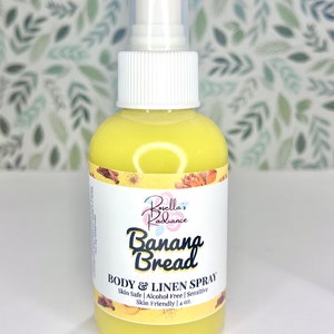 May include: A yellow bottle of Banana Bread Body & Linen Spray by Borella's Radiance. The bottle is labeled with the product name and description, including the size: 4 oz. The bottle has a white spray nozzle.