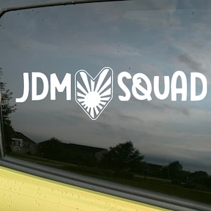 May include: A white vinyl sticker with the text "JDM" followed by a stylized heart with a rising sun design and the text "SQUAD".