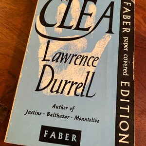 May include: A blue book cover with the title "CLEA" in large black letters. The author's name, "Lawrence Durrell", is written in a stylized font below the title. The book is a "Faber Paper Covered Edition" and the author is noted as the author of "Justine, Balthazar, Mountolive".