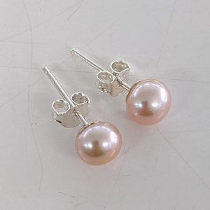 Pode incluir: Um par de brincos de prata com detalhes de pérolas cor-de-rosa.