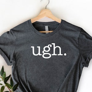 May include: A dark gray t-shirt with the word "ugh." printed in white on the front.