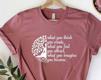 Può includere: Una t-shirt color malva heather con un design a forma di albero bianco e il testo "what you think you create, what you feel you attract, what you imagine you become."