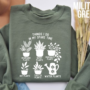 May include: A green sweatshirt with a white graphic that says "Things I do in my spare time" and lists plant-related activities like "Rearrange Plants", "Repot Plants", "Propagate Plants", "Buy Plants", "Talk to Plants", and "Water Plants".