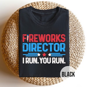 May include: Black t-shirt with the text "FIREWORKS DIRECTOR" in red and blue. The shirt also has the text "I RUN. YOU RUN." and two stars. The word "BLACK" is in a white circle.