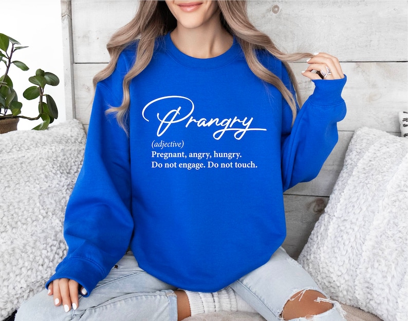 May include: A royal blue sweatshirt with white text that reads "Prangry (adjective) Pregnant, angry, hungry. Do not engage. Do not touch."