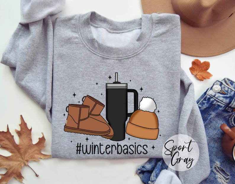 May include: Gray sweatshirt with a graphic design of a coffee cup, a beanie, and a pair of brown boots. The text "#winterbasics" is printed on the sweatshirt.