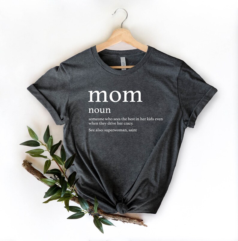 May include: A dark gray t-shirt with the word "mom" defined as "someone who sees the best in her kids even when they drive her crazy." The definition also includes "See also: superwoman, saint."