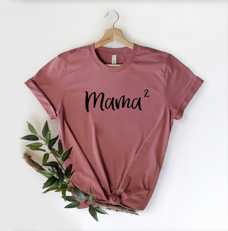 以下が含まれることがあります： マウブ色のTシャツに、黒い文字で「Mama^2」と書かれています。