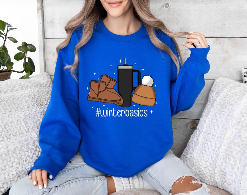 May include: A royal blue sweatshirt with a graphic design of a coffee cup, a beanie, and a pair of brown winter boots. The text "#winterbasics" is printed below the graphic.