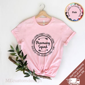 May include: Pink t-shirt with a black circle graphic that says "Pharmacy Squad" surrounded by the words "Warm, Compassionate, Caring, Loving, Dedicated, Fun, Reliable, Loyal, Kind".