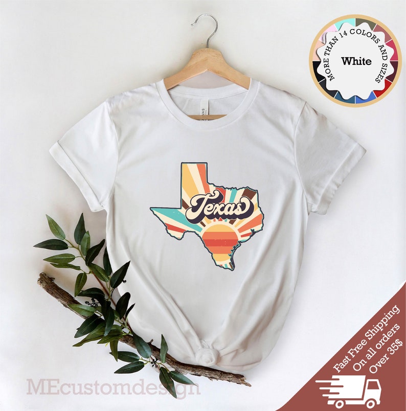 May include: White t-shirt with a retro-style graphic of the state of Texas with a sunrise and the word "Texas" in a vintage font.
