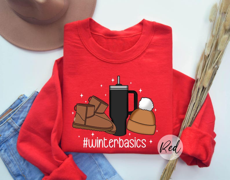 May include: Red sweatshirt with a graphic design of a coffee cup, a pair of brown boots, and a winter hat. The text "#winterbasics" is printed below the graphic. The word "Red" is written in white text on a red circle in the bottom right corner of the image.