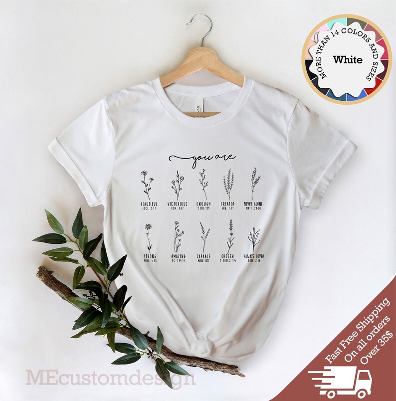 May include: White t-shirt with a floral design and the text "you are" with bible verses listed below each flower.