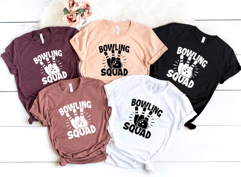 May include: Five different colored t-shirts with the text "Bowling Squad" and a graphic of bowling pins and a bowling ball.