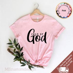 May include: Pink t-shirt with the text "CHILD OF GOD" in black script lettering.