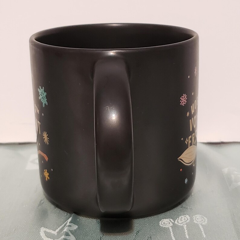 May include: Black ceramic mug with a white handle and colorful designs. The mug has the text "What you do for yourself, you do for your friends." printed on it.