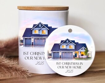 Könnte beinhalten: Ein weißer Keramiktopf mit Holzdeckel und ein runder Ornament. Beide zeigen eine Hausillustration mit dem Text "1st Christmas in Our New Home 2025". Das Haus hat ein blaues Dach und eine Doppelgarage.
