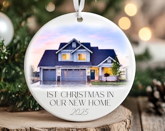 Könnte beinhalten: Runder, weißer Weihnachtsschmuck mit einer Hausillustration. Das Haus hat ein blaues Dach und hellblaue Wände. Der Text "1st Christmas in Our New Home 2025" ist auf dem Ornament aufgedruckt. Ein weißes Band ist zum Aufhängen befestigt.