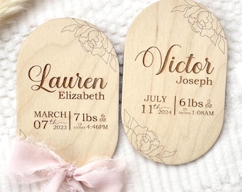 Könnte beinhalten: Zwei Holz-Geburtsanzeigen mit eingravierten Namen, Geburtsdaten und Gewichten. Auf einer steht "Lauren Elizabeth" mit den Details vom 7. März 2023, 3,2 kg. Auf der anderen steht "Victor Joseph", geboren am 11. Juli 2024, 2,7 kg.